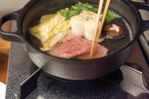 东京cyashitsu ryokan asakusa的火炉上装满食物的锅,有筷子
