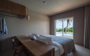 宫古岛アヤンナ宮古島的一间卧室配有一张床、一张桌子和一个窗户。