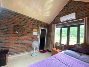 吉婆岛Cat Ba Rustic Homestay的一间卧室设有砖墙、一张床和一个风扇