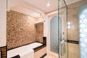 迪拜Al Habtoor Grand Resort, Autograph Collection的带浴缸和玻璃淋浴间的浴室。