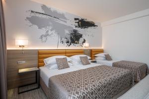 杜布罗夫尼克伊夫卡酒店的一间卧室设有两张床,墙上挂着一幅画
