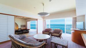 田原市伊良湖度假&会议酒店的客厅配有桌椅和电视
