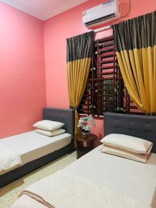 Kampung RajaTeratak Ammara Homestay Besut with private pool的配有粉红色墙壁的客房内的两张床