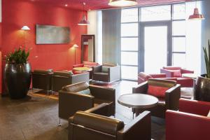 南希南希中心诺富特套房酒店的一间设有桌椅和红色墙壁的等候室