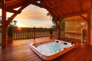 AlzonneCabane de Prestige avec Jacuzzi et Sauna privatifs的木制甲板上的热水浴池,享有日落美景