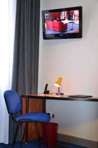 圣阿沃尔德Logis Hotel de Paris的客房设有书桌和墙上的电视。