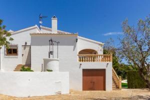哈维亚Chalet Los Olivos con piscina的白色的房子,有木门和门