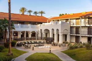 棕榈荒漠Embassy Suites by Hilton Palm Desert的一座带桌椅的建筑的庭院