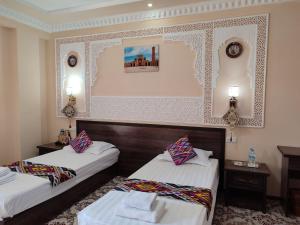 布哈拉Hotel Shams的酒店客房,设有两张床和两张桌子