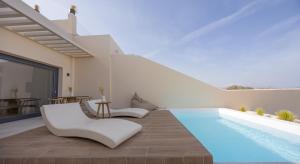 费拉Pnoe Luxury Suites的别墅设有游泳池和白色家具