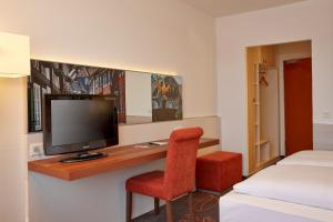 戈斯拉尔戈斯拉尔H+酒店的一间卧室配有一张桌子、一台电视和一把椅子