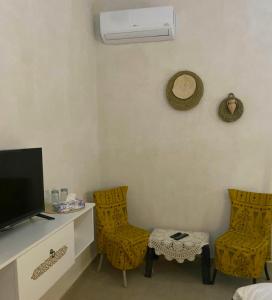 米多恩Djerba Rêve Vacances Emna EL Beya的客房设有2把椅子和1张带电视的书桌。