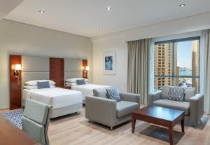 迪拜朱美拉海滩华美达广场酒店的酒店客房设有两张床和一张桌子。