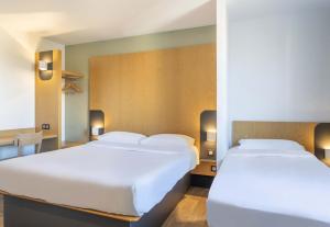 布克港B&B HOTEL Martigues Port-de-Bouc的配有桌子的客房内的2张白色床