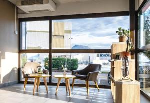 格勒诺布尔B&B HOTEL Grenoble Centre Verlaine的客房设有2把椅子和桌子以及大窗户。
