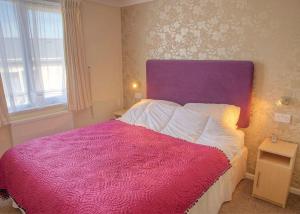 阿博波恩Gwalia Falls的一间卧室配有一张大床和紫色床头板