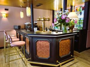 贝尔韦Logis Hôtel Le Boudoir的餐厅内的酒吧,设有粉红色凳子