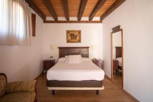 夸科斯德尤斯特亚巴迪亚德乌斯特乡村酒店 的一间卧室配有一张床、一张沙发和一面镜子