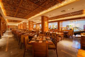 乌纳瓦图纳Araliya Beach Resort & Spa Unawatuna的一间带木桌椅的餐厅和一间酒吧