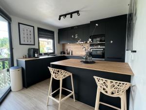 瑟兰Duplex 100m2 style contemporain的厨房配有黑色橱柜和带2张凳子的台面