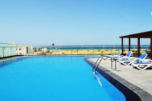苏尔Sur Grand Hotel的一个带躺椅的游泳池和海滩