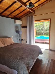 蒂拉登特斯Chalés da Estrada Velha的一间卧室配有一张床,享有游泳池的景色