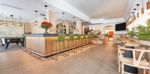 卡拉纳雅达Flacalco Hotel & Apartments的餐厅设有酒吧,配有绿色的桌椅