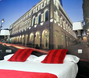 巴利亚多利德艾勒恩纳拉精品酒店的大楼前一张带红色枕头的床