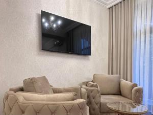 埃里温Armenia Hotel的客厅配有两把椅子和墙上的电视