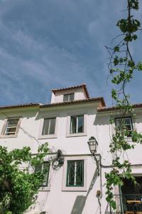 里斯本Casa da Maria Alfama的白色的建筑,设有窗户和街灯