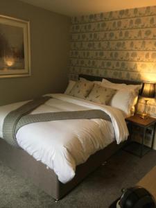 奥尔戈斯OYO Auldgirth Inn的卧室配有一张带白色床单和枕头的大床。