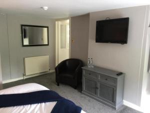 奥尔戈斯OYO Auldgirth Inn的一间卧室配有一张床、一把椅子和电视