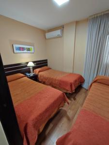 圣米格尔·德·图库玛弗朗西亚酒店的酒店客房,配有3张带橙色床单的床