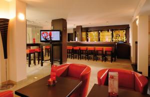 慕尼黑莱昂纳多酒店慕尼黑市中心的餐厅设有酒吧、红色椅子和电视