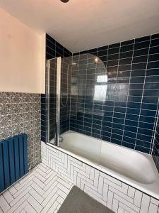 KentDartford Stay的带浴缸和蓝色瓷砖的浴室