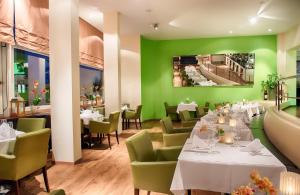 苏黎世苏黎世雷奥纳多精品酒店的用餐室设有白色桌子和绿色墙壁