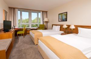 科隆科隆波恩机场莱昂纳多酒店的酒店客房设有两张床、一张桌子和一台电视。