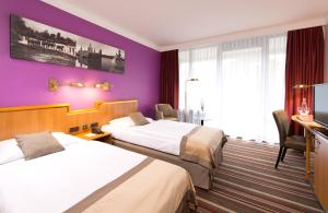 汉诺威汉诺威莱昂纳多酒店的酒店客房设有两张床和紫色的墙壁。