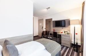 纽伦堡纽伦堡莱昂纳多酒店的配有一张床和一张书桌的酒店客房