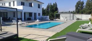 KitiKiti Village Villa Larnaca, salt-water pool, 5 bedrooms的一个带游泳池和房子的后院