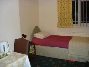 曼彻斯特维多利亚公园酒店的一间卧室设有一张床、一个窗口和一张桌子