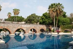 特克塞丁戈何尔摩沙景观庄园酒店的一座古老的石头桥,在棕榈树游泳池上