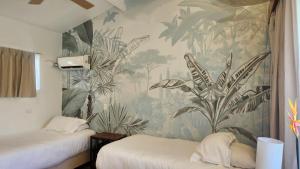 圣安德烈斯可可普拉姆海滩酒店的一间卧室设有两张床和热带壁纸