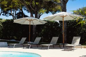 雷以桑布尔LA VILLA ALBA的游泳池畔的2把遮阳伞和躺椅