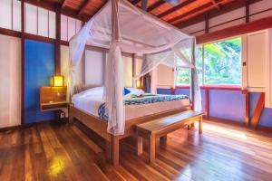 别霍港Namuwoki Lodge的一间卧室设有一张天蓬床和木地板。