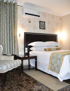 利隆圭Annavilla7 Lilongwe Aparthotel的配有一张床和一把椅子的酒店客房