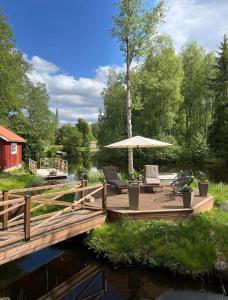 NorbergPastors Prästgården的河上带椅子和遮阳伞的木制甲板