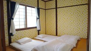 Higashikagura東神楽大学ゲストハウス的带窗户的客房内的两张床
