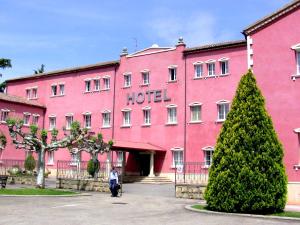 纳瓦雷特圣卡米洛酒店的粉红色的酒店,前面有一位女士