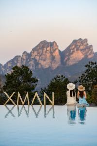 张家界XMAN Valley Sunrise Resort的两人坐在水中,背景是山